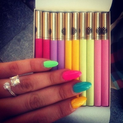 Цветные сигареты в руках с разноцветными ногтями