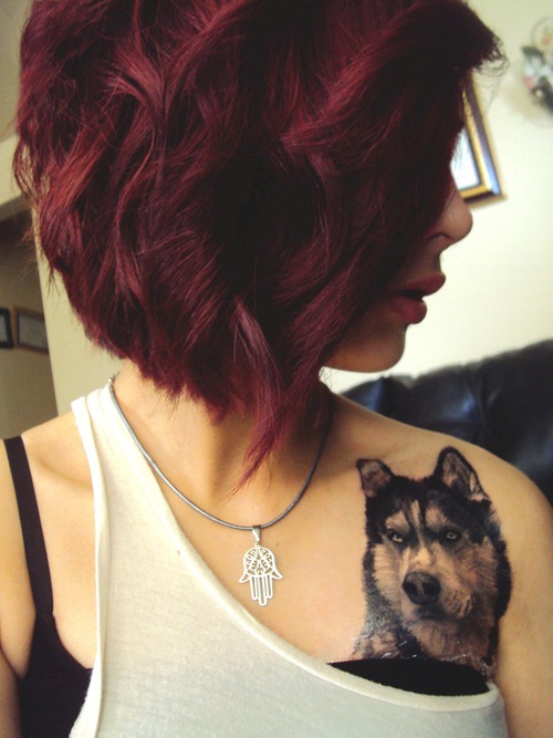 Девушка с красными волосами с тату волком на груди