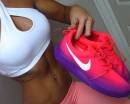 Девушка держит розово-фиолетовые кроссовки Nike
