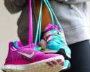 Бирюзовые и розовые кроссовки Nike в руках девушки