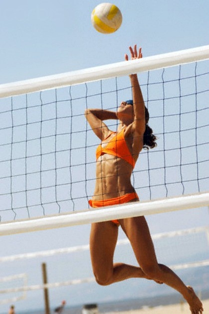 Девушка в прыжке за игрой в пляжный волейбол
