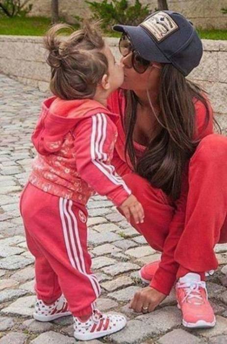 мама целует малышку дочку в спортивном костюме
