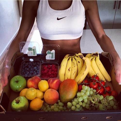Девушка в белом топе Nike с овощами и фруктами