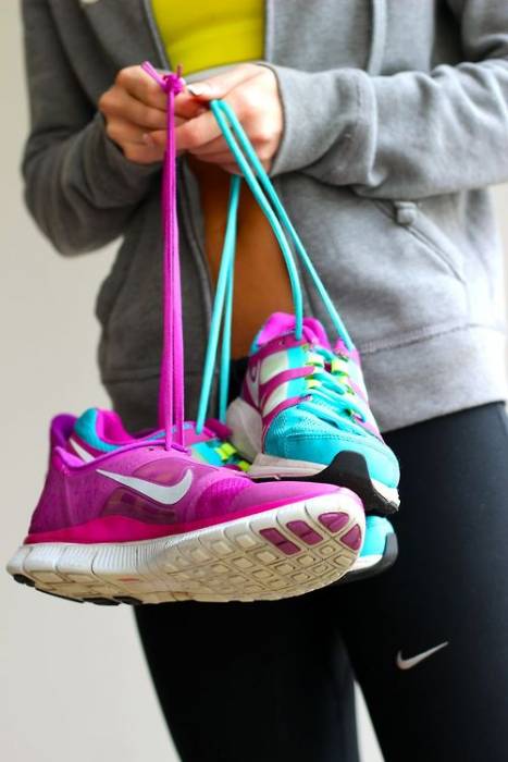 Бирюзовые и розовые кроссовки Nike в руках девушки