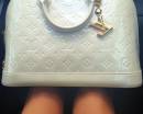 Белая сумка Yves Saint Laurent на коленях девушки