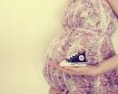 Беременная женщина держит кеды для малыша