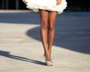 Загорелые ноги девушки в белом платье
