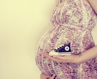 Беременная женщина держит кеды для малыша