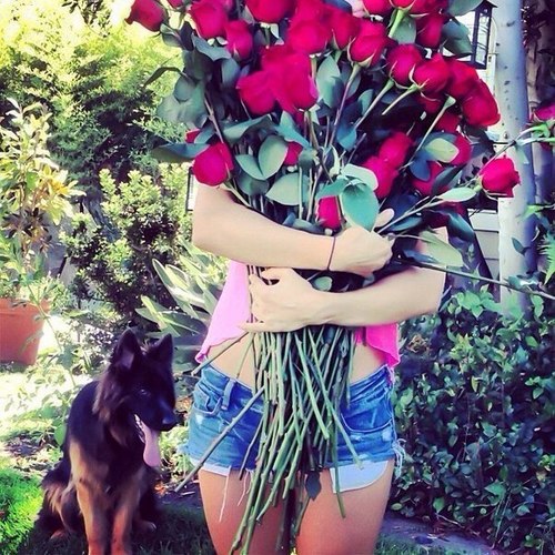 Девушка в джинсовых шортах с огромным букетом роз