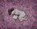 Девушка на розовой цветочной поляне читает книгу