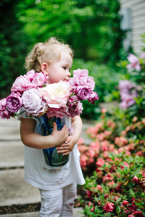 Девочка держит вазу с розами в саду