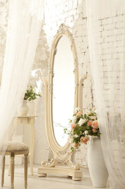 Большое овальное зеркало и напольная ваза с розами