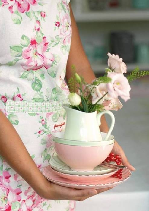 Девушка в цветастом платье держит чайный сервиз
