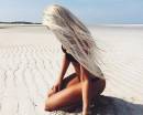 Длинные пепельные волосы девушки на песке пляжа