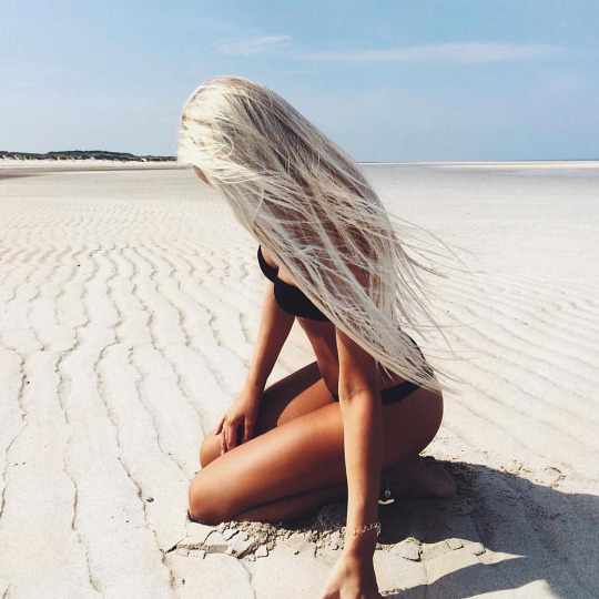 Длинные пепельные волосы девушки на песке пляжа