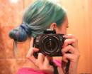 Девушка с зелеными волосами держит фотоаппарат